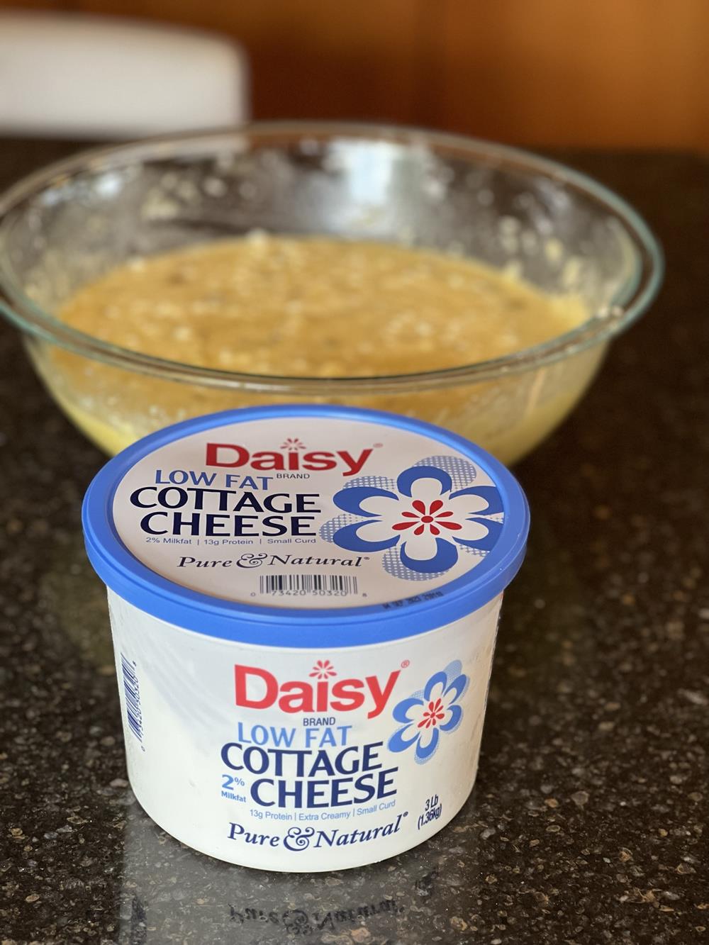 cottage cheese in container with bowl of unbaked quiche in background