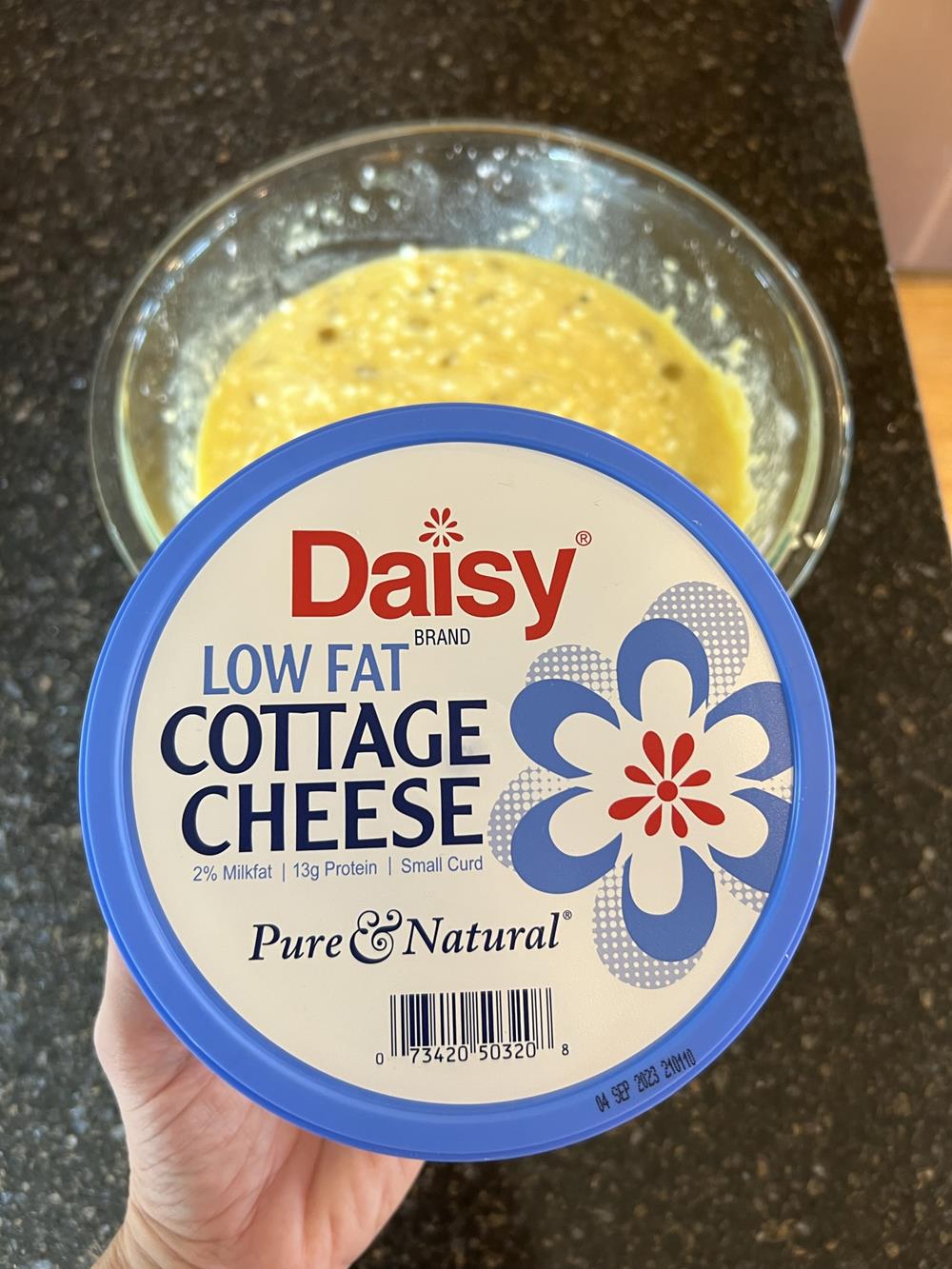 unbaked cottage cheese quiche in glass bowl with container of daisy cottage cheese