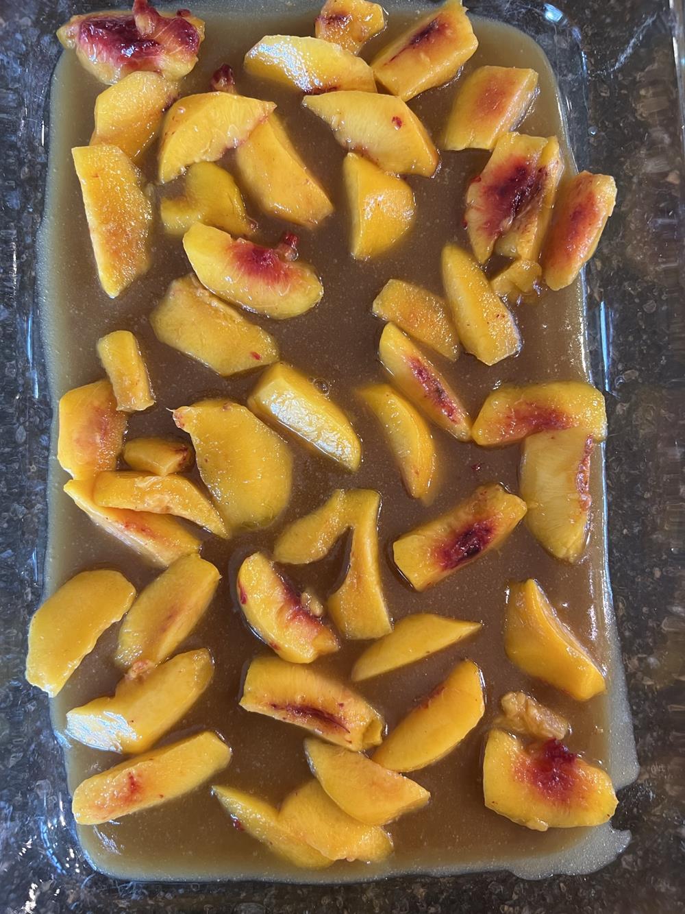 peaches and syrup in glass pan