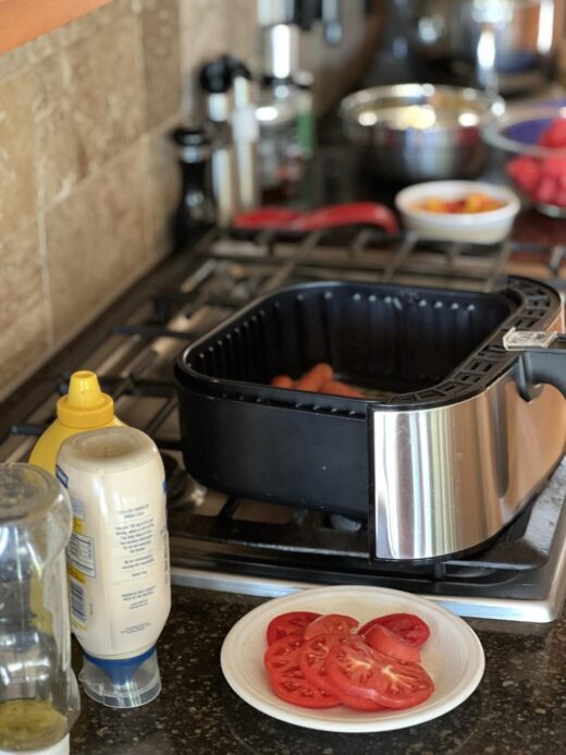 air fryer hot dogs, tomatoes, and fruit on a counter and stove top