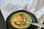Martha Stewart's Broccoli Soup in a black bowl with spoon on white napkin