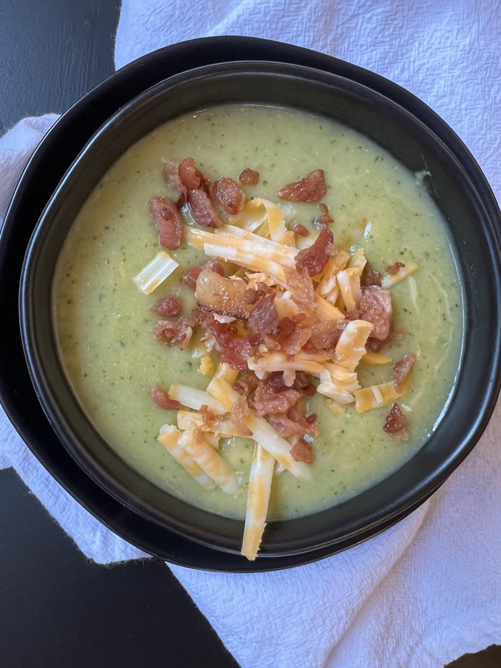 broccoli soup with bacon and cheese in black bowl