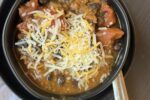 Slow Cooked Pumpkin Chili in black bowl on black plate with white napkin