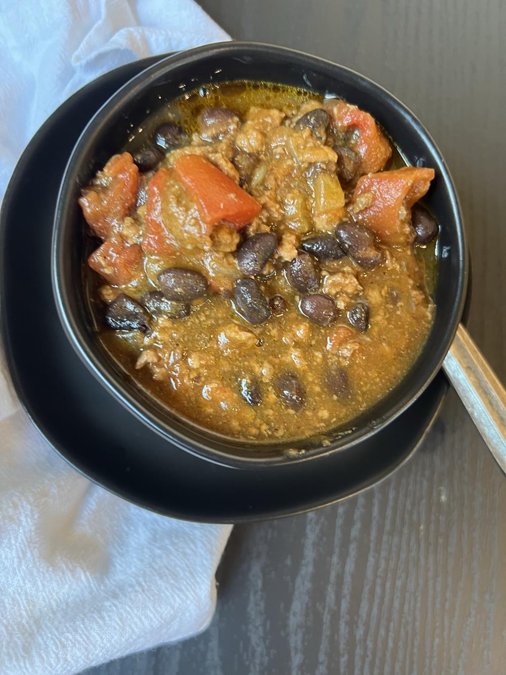 pumpkin chili in black bowl with spoon