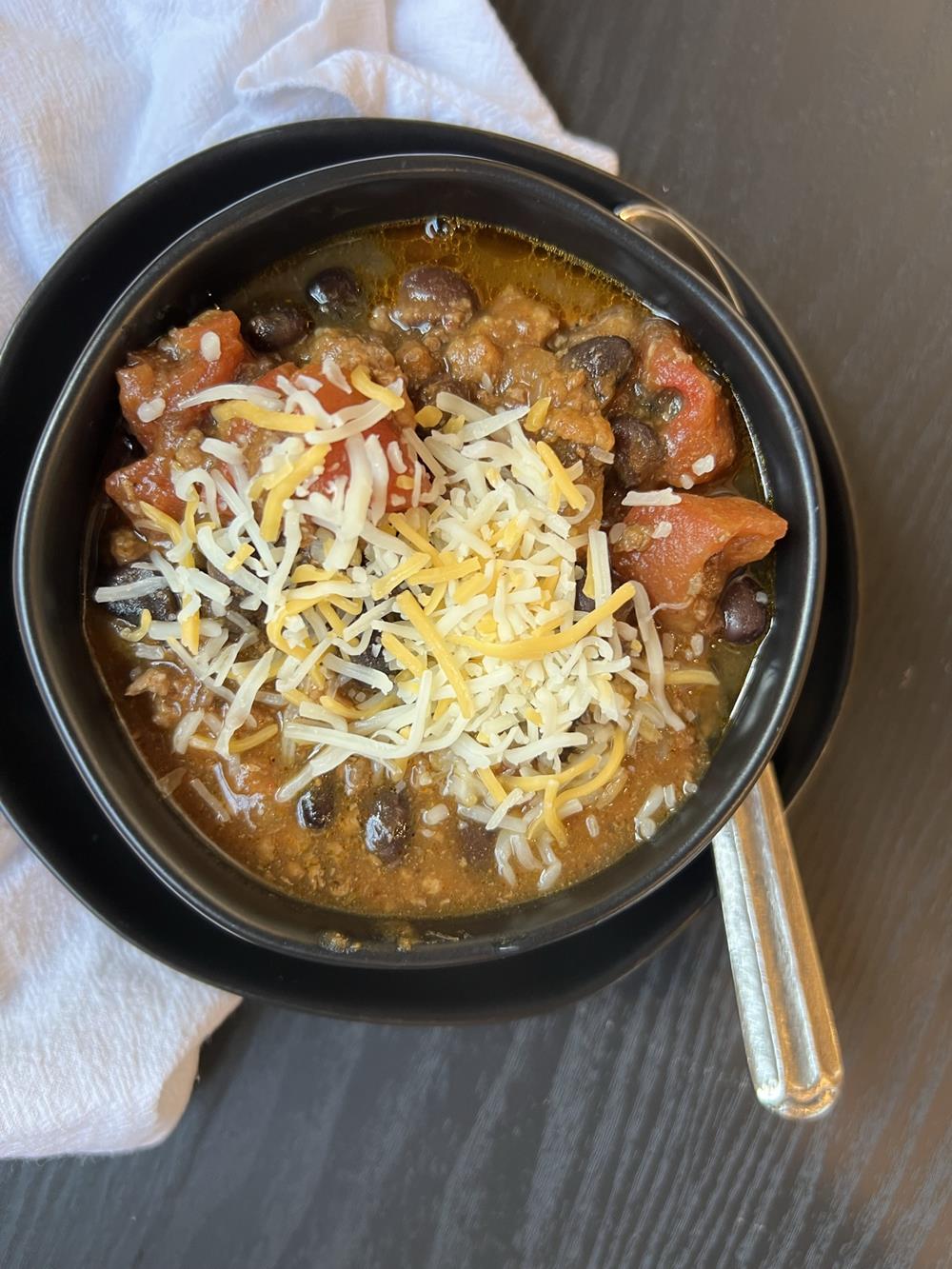 Slow Cooked Pumpkin Chili in black bowl on black plate with white napkin