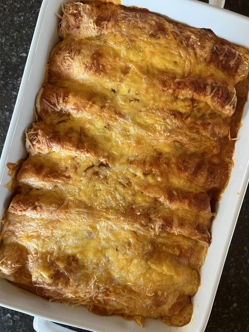 cheese and chicken enchiladas in white pan