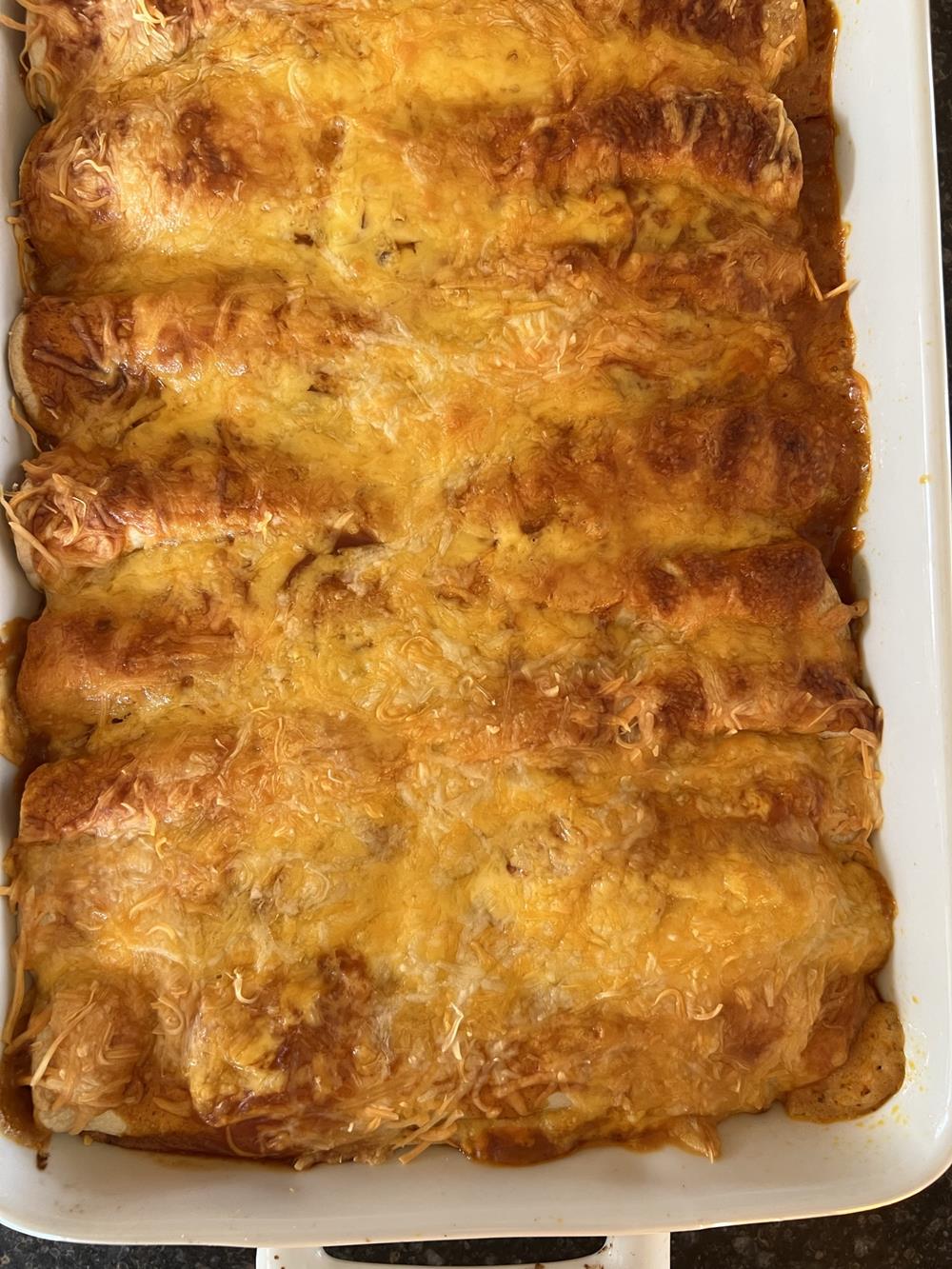 Cheese and chicken enchiladas in white pan
