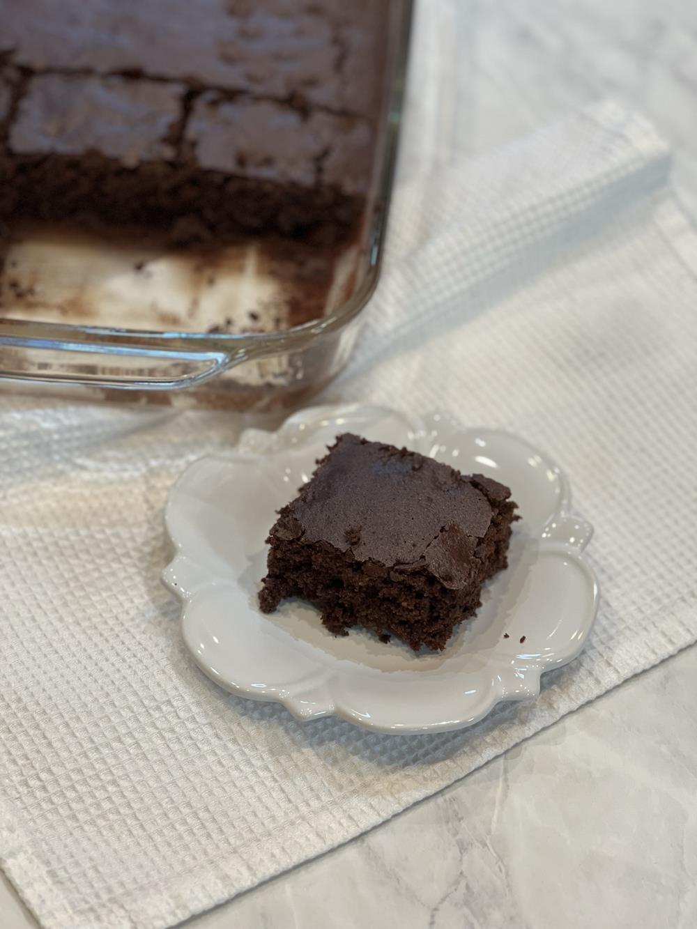 chocolate brownies on white plate with glass pan in background