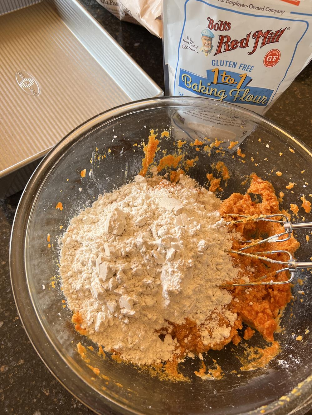 gluten free pumpkin bar batter in glass mixing bowl with pan in the background