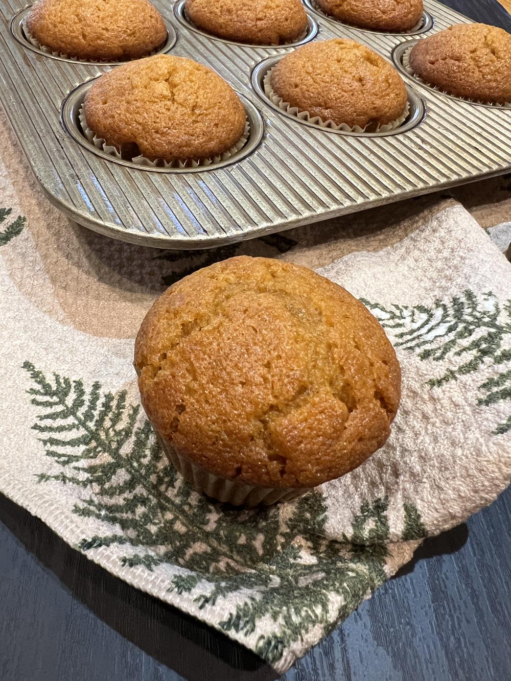 pumpkin muffin on green and tan napkin with muffin pan in background