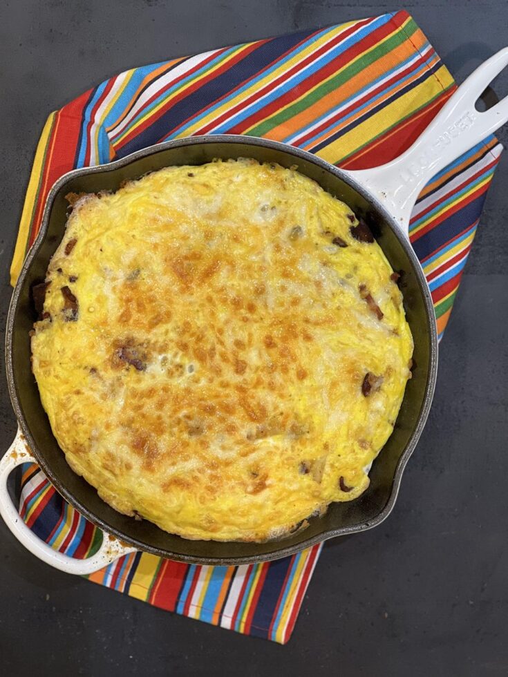 Apple Bacon Cheese Frittata on cast iron pan on striped towel