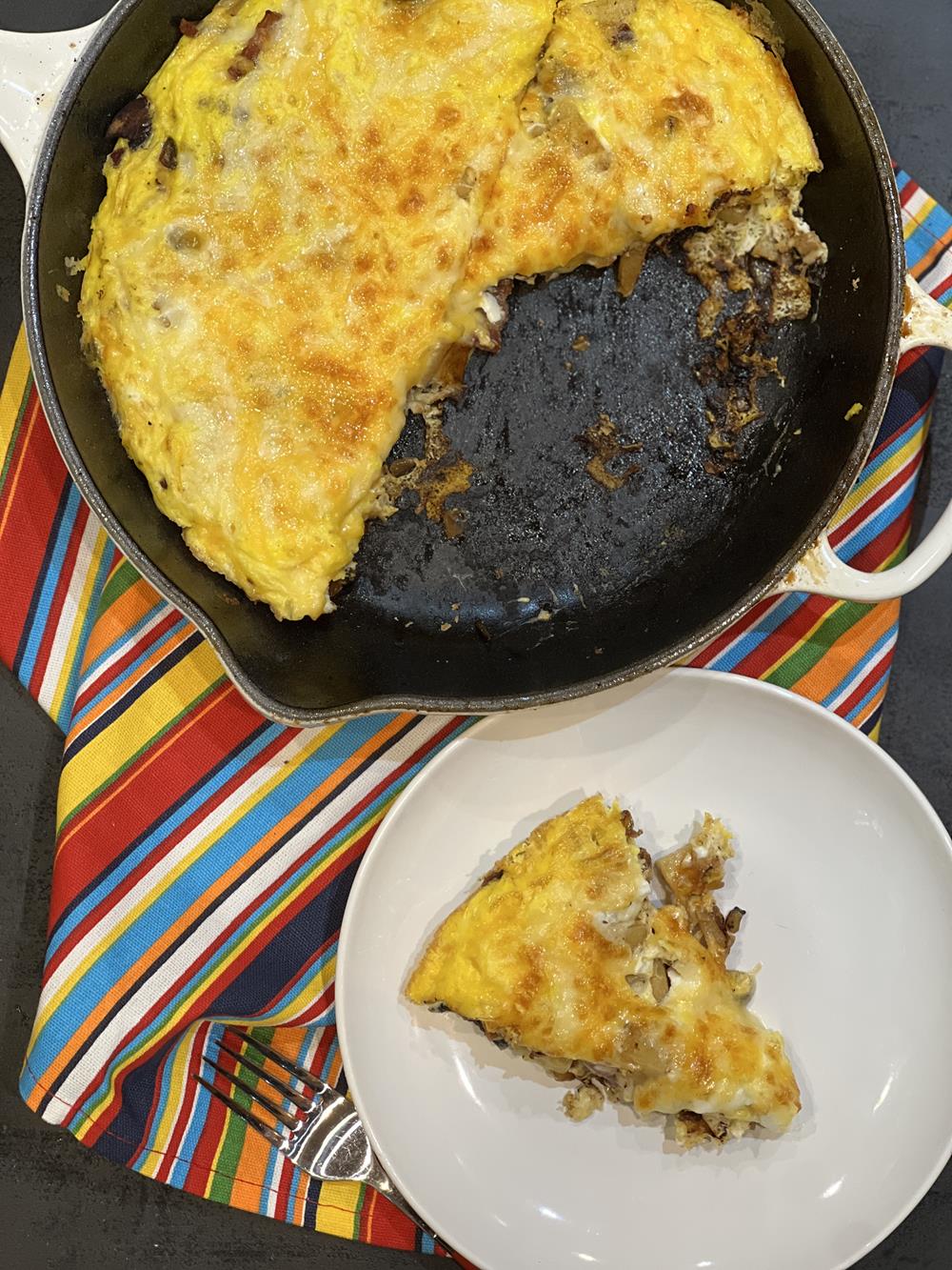 Apple Bacon Cheese Frittata on white plate and in cast iron pan in the background