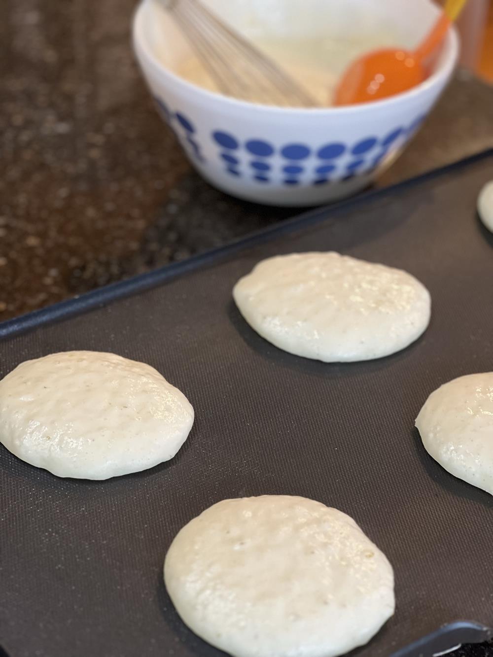 pancakes cooking on a griddle