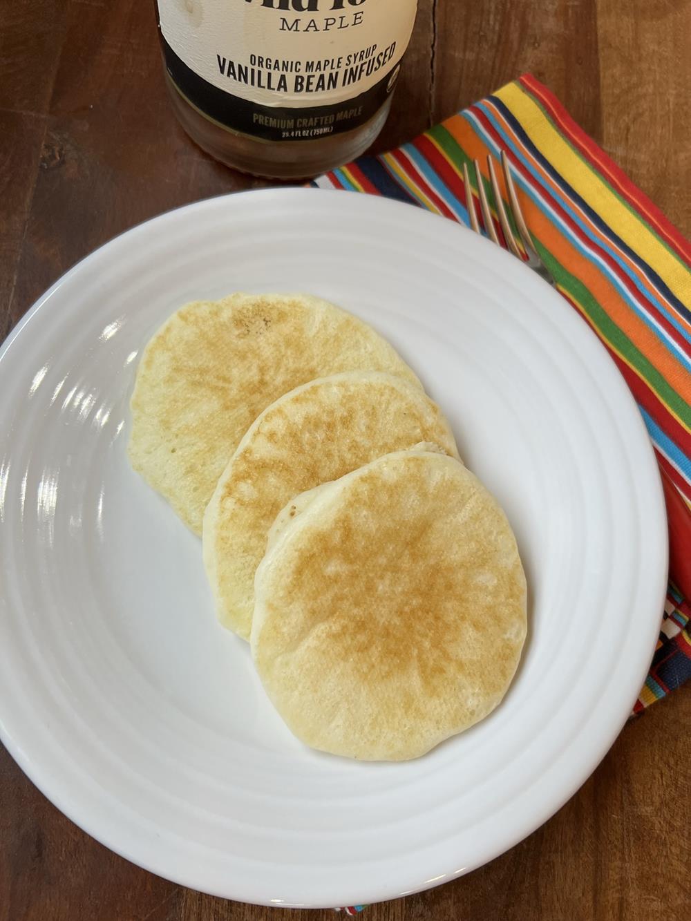 pancakes on a white plate with syrup in the background