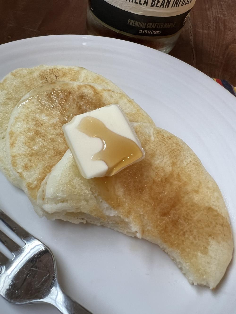 pancakes butter and syrup on a white plate