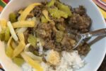 ground beef, rice, pickles, and cheese in white bowl on stiped napkin