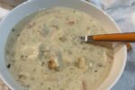 gluten free chicken and rice soup in white bowl with spoon with orange handle