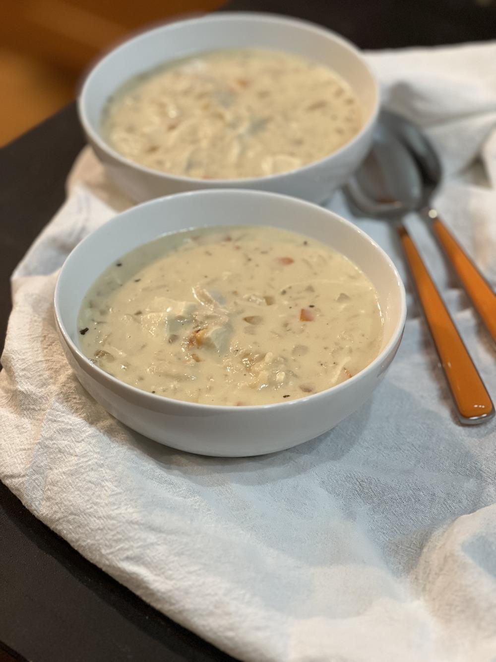 chicken and rice soup in white bowls on white napkin