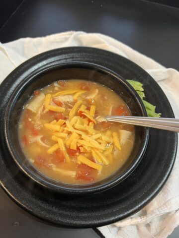 chicken and cheese soup in black bowl with spoon