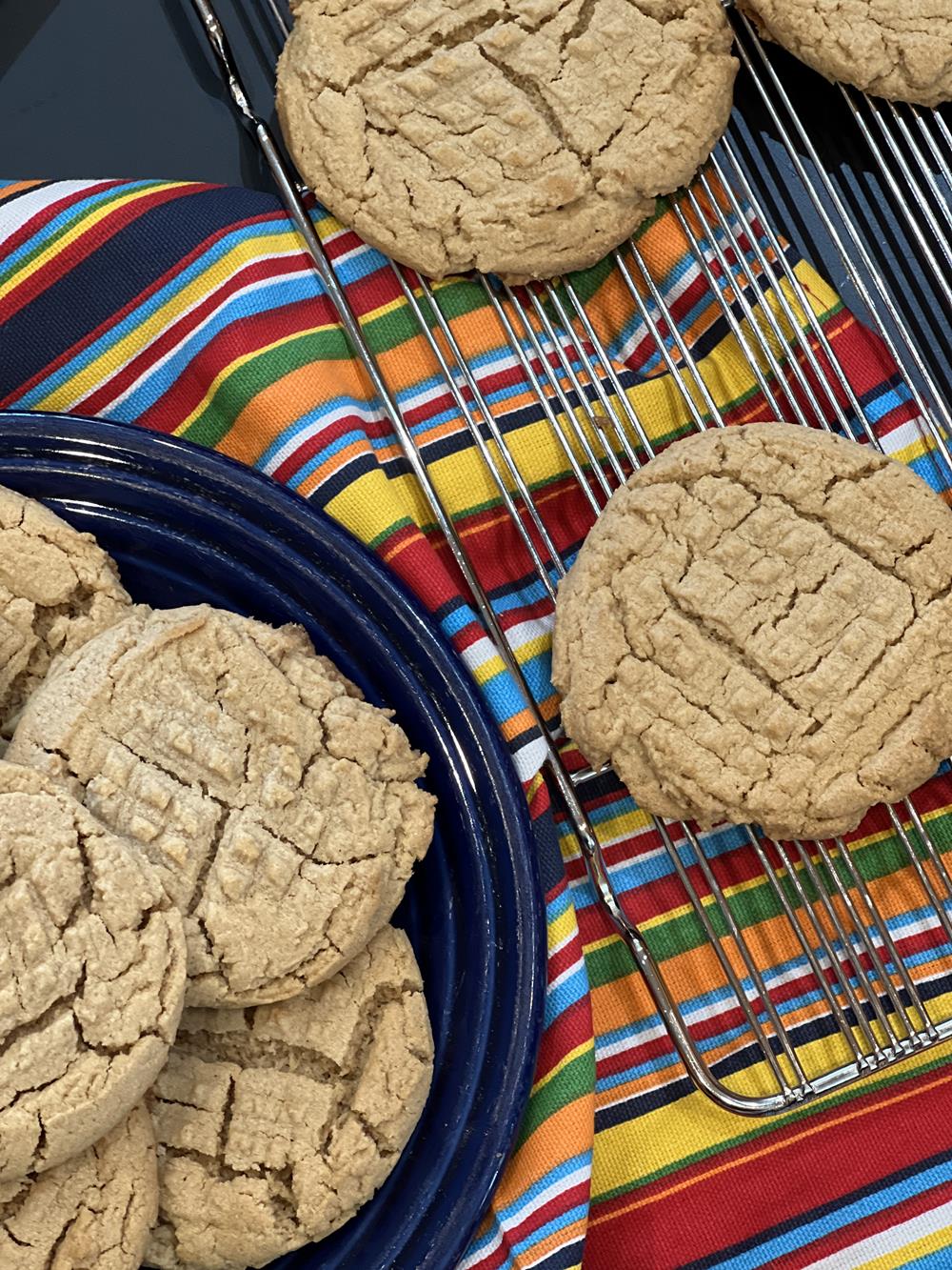Peanut butter cookies on blue plate with striped napkin and cooling rack in back