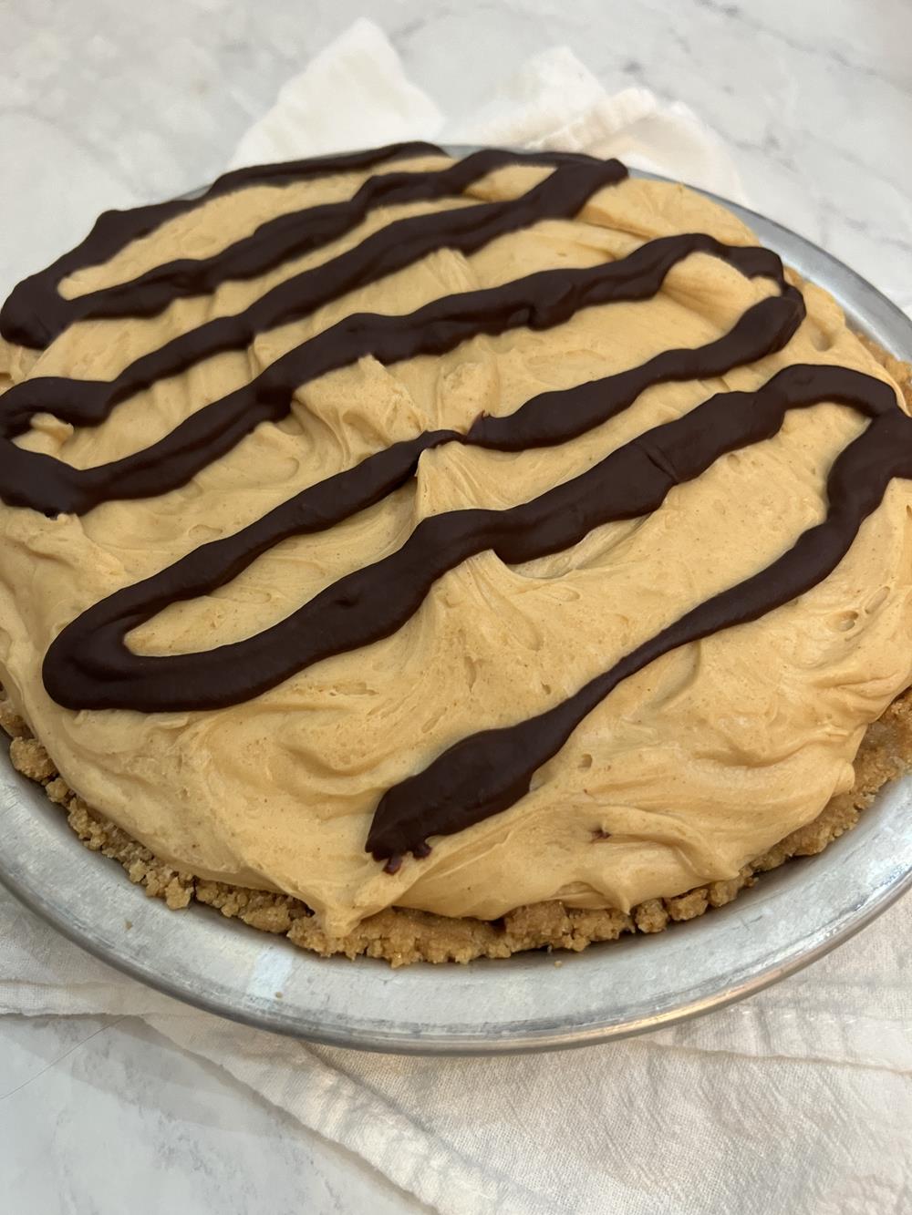 peanut butter chocolate pie in tin pie plate on white background