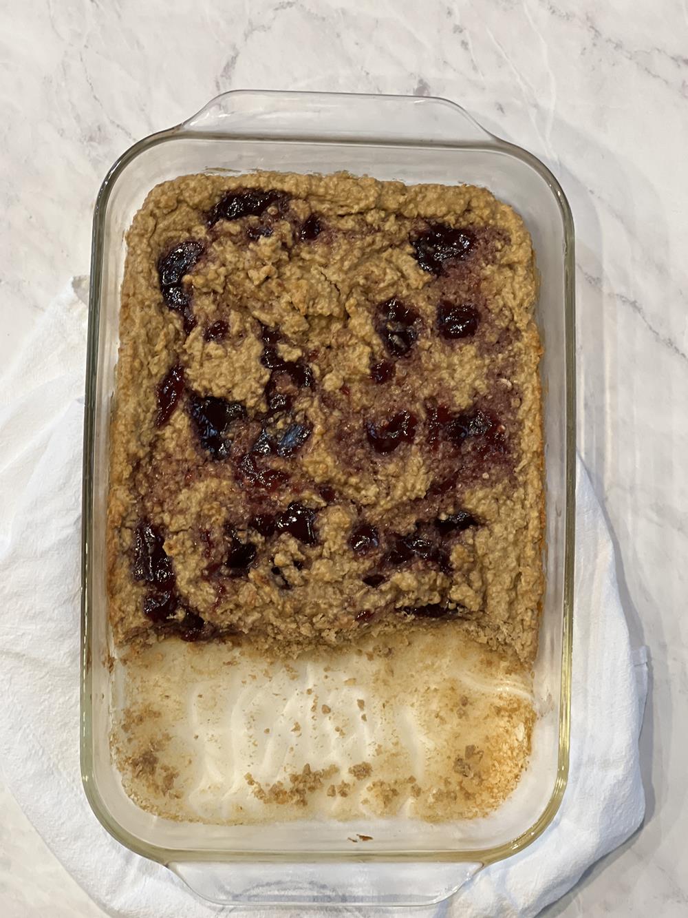 Peanut Butter and Jelly Baked Oatmeal squares in glass pan on white background