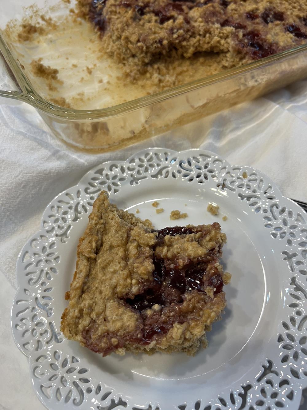 Peanut butter baked oatmeal on white plate with glass pan in background