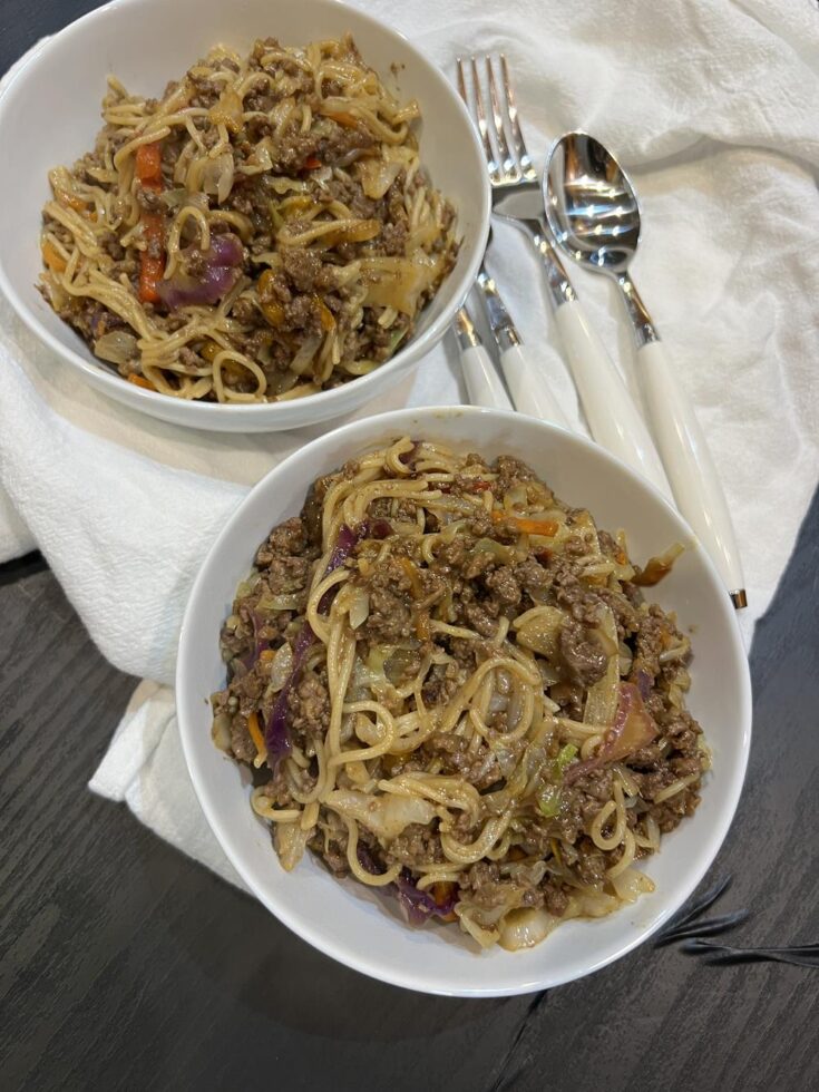 noodle stir fry in white bowls with silverware next to bowls