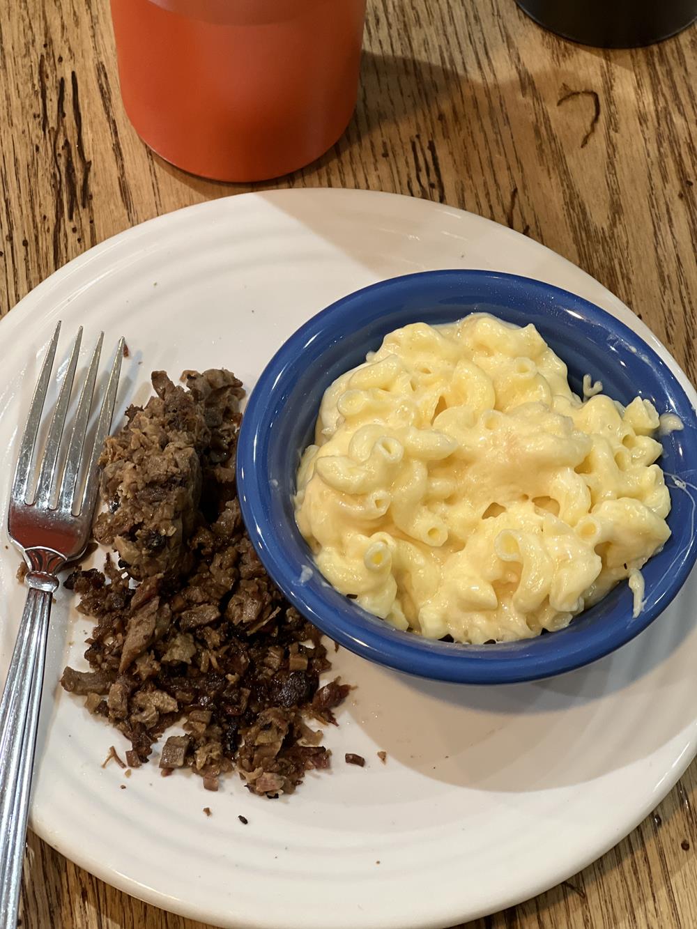 bbq meat on white plate next to mac and cheese