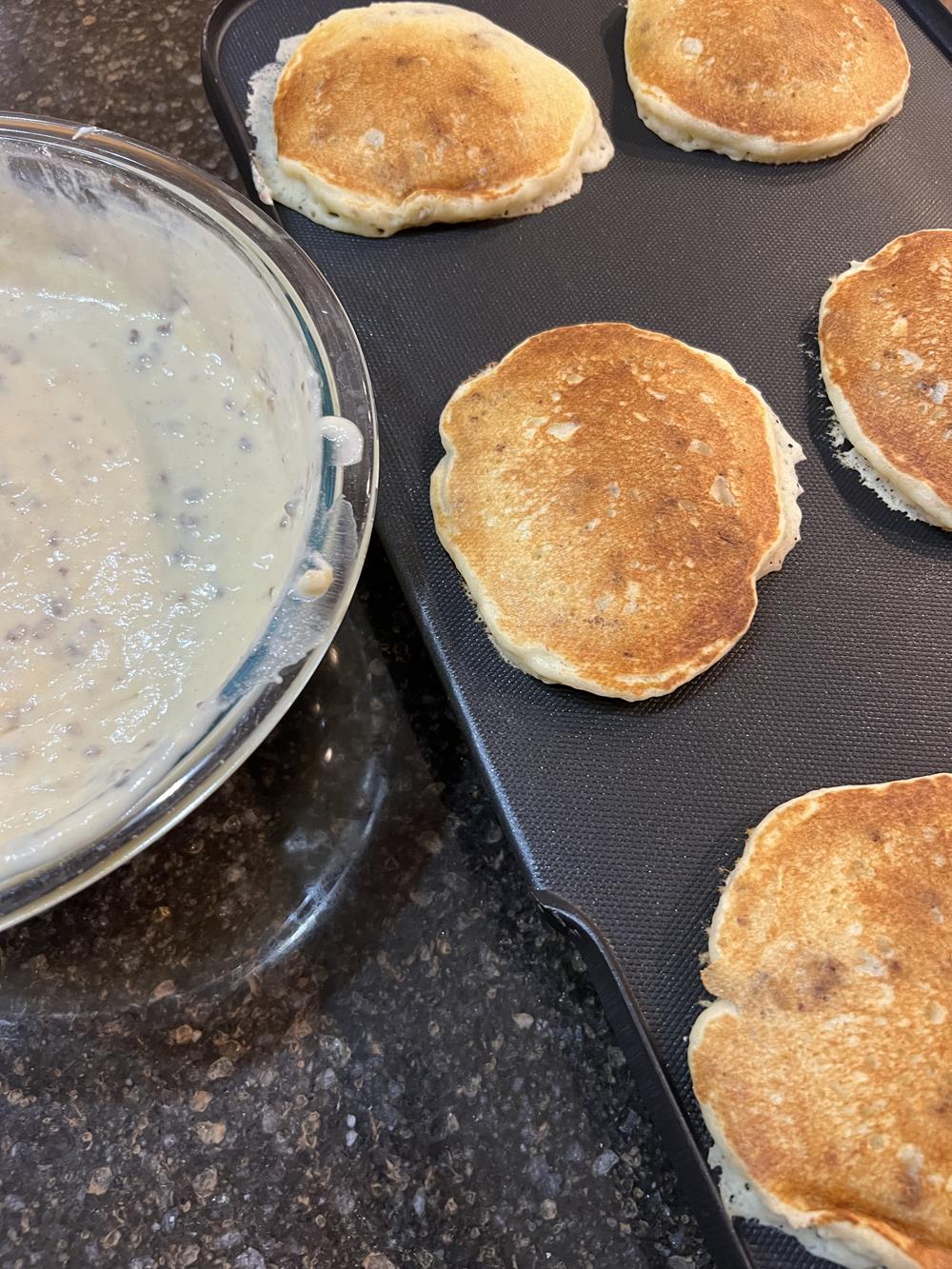 pancakes on griddle with bowl of pancake batter
