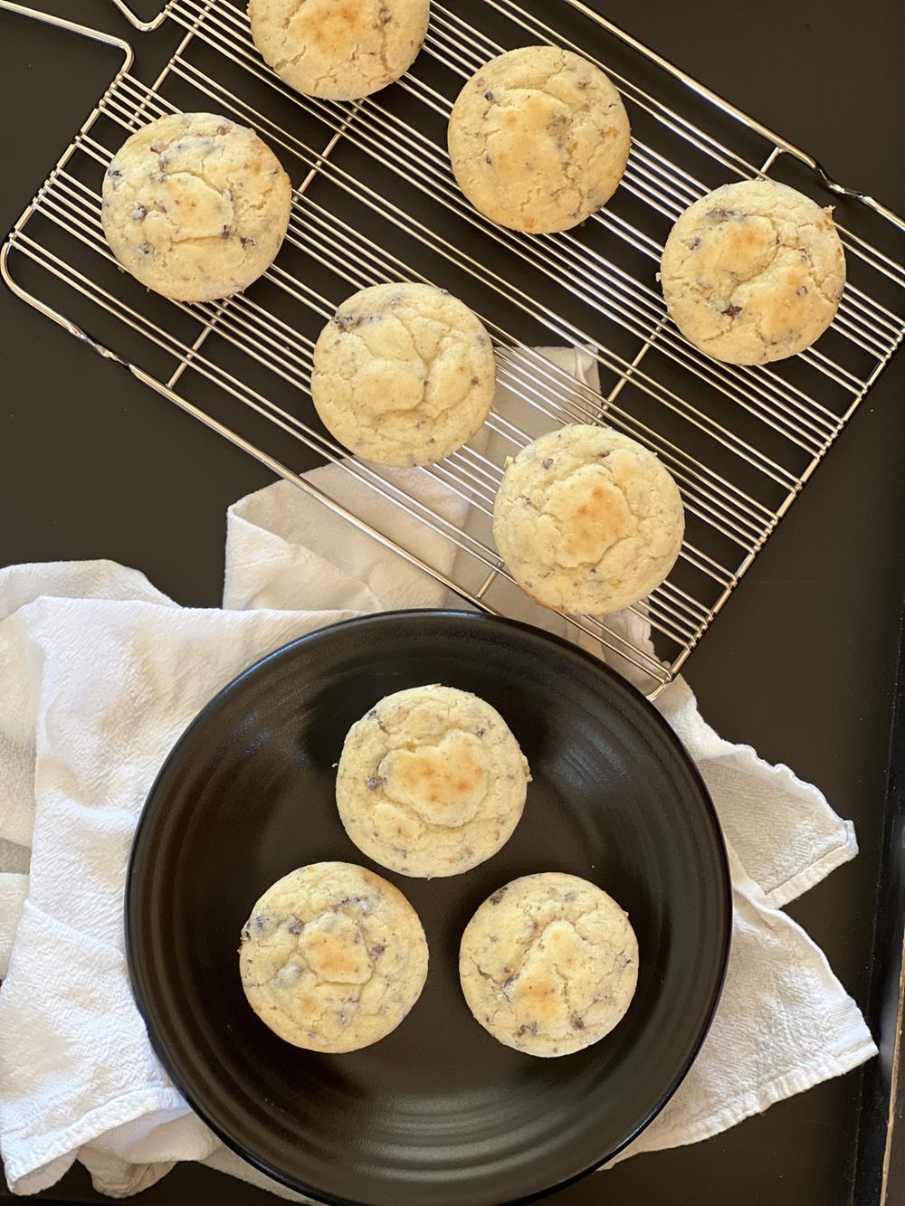 sausage maple pancake muffins on black plate with muffins on cooling rack in background