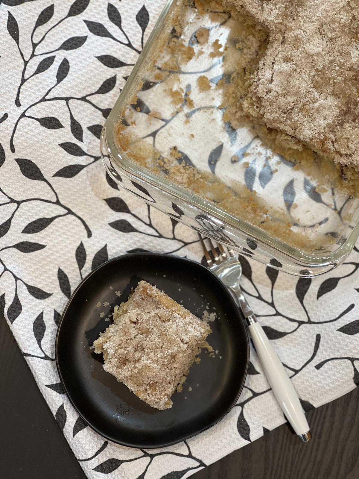 rhubarb cake on black plate with cake in glass pan in background