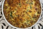 spinach sausage quiche in white dish on black and white floral cloth