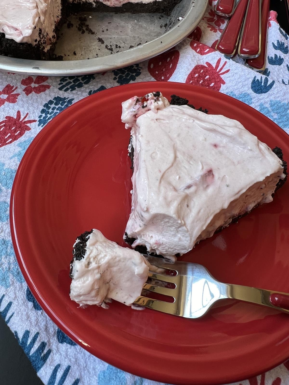 piece of no bake berry pie with gluten free crust on red plate with red and silver silverware