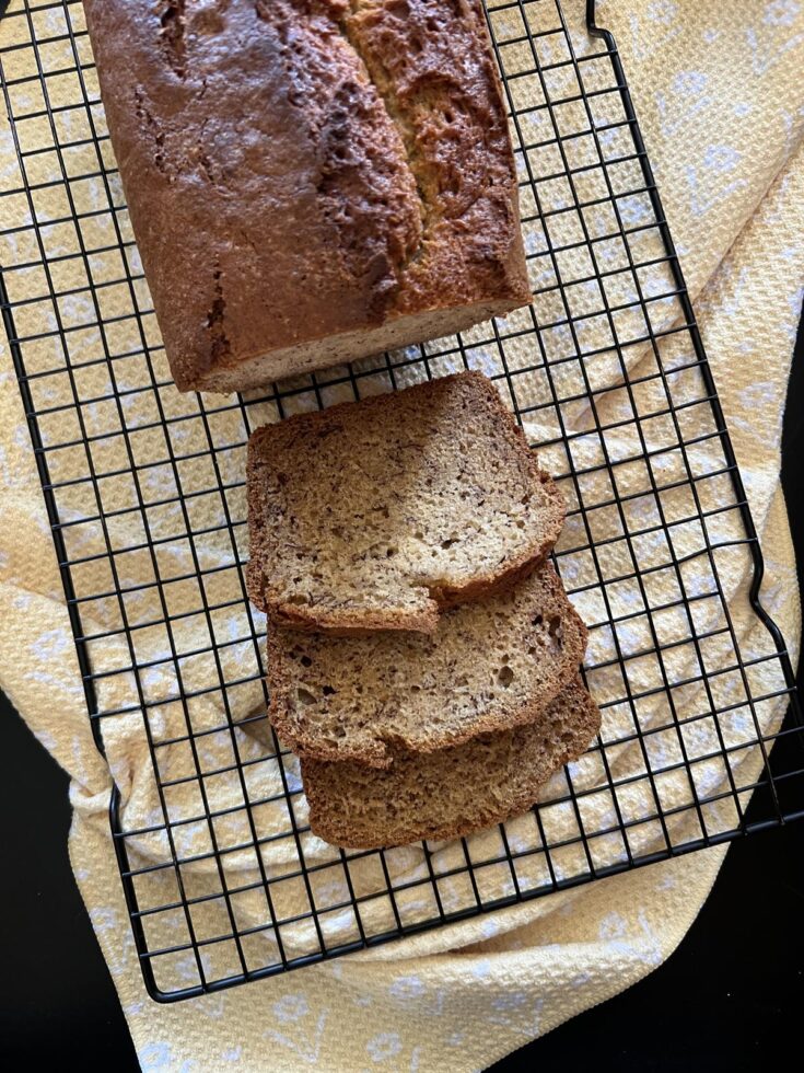 loaf of dairy free banana bread with slices on cooling rack