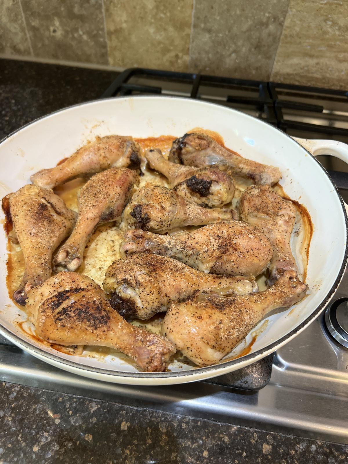 baked chicken legs in white cast iron pan
