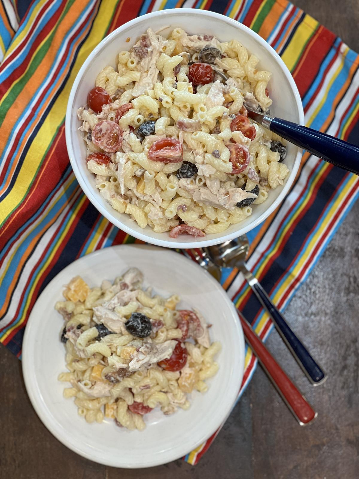 chicken bacon ranch pasta salad in white bowl on striped napkin with blue and red silverware