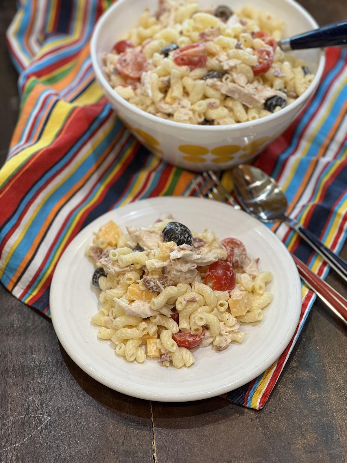 Chicken Bacon Ranch Pasta Salad in white and yellow bowl and on white plate on striped napkin