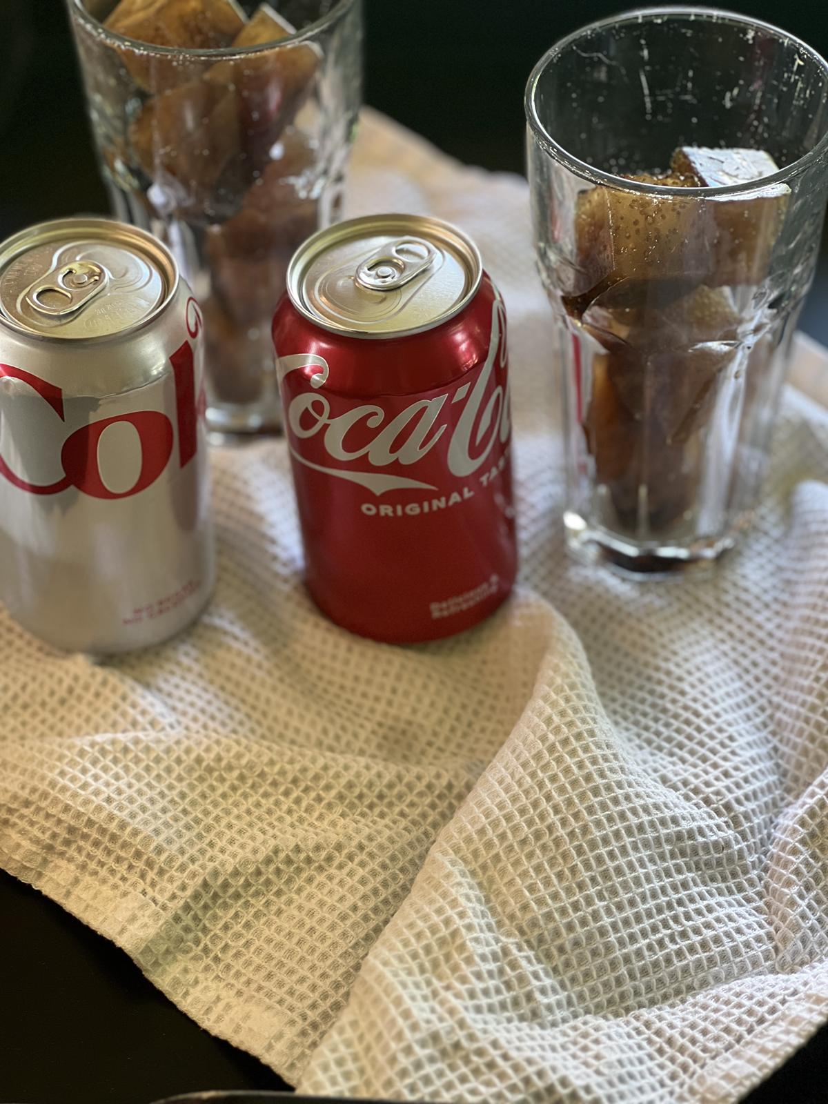coke and diet coke next to a glass with ice cubes