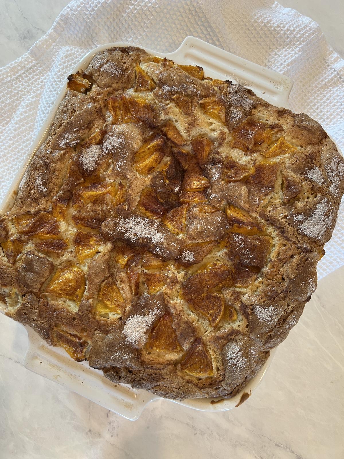 fresh peach cake in white pan on white napkin