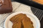 sliced gluten free pumpkin bread on white plate with loaf of bread in background