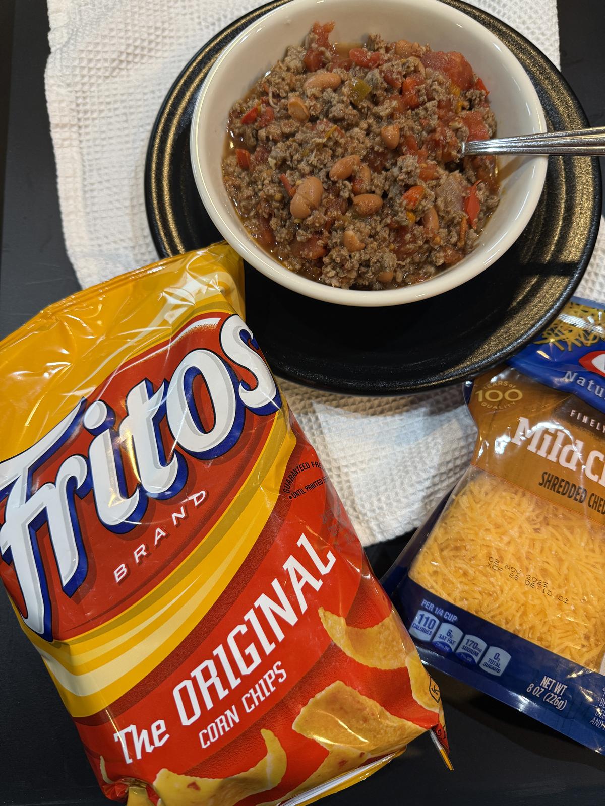 bowl of deer chili in white bowl with fritos and shredded cheese
