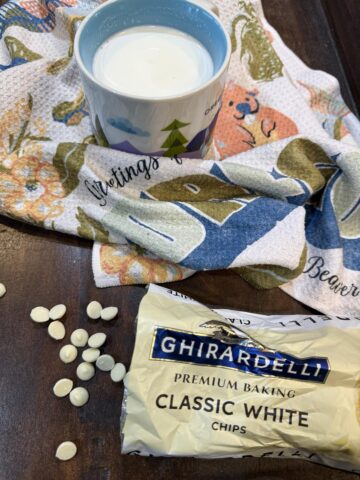 white hot chocolate in a mug with white chocolate chips on black background