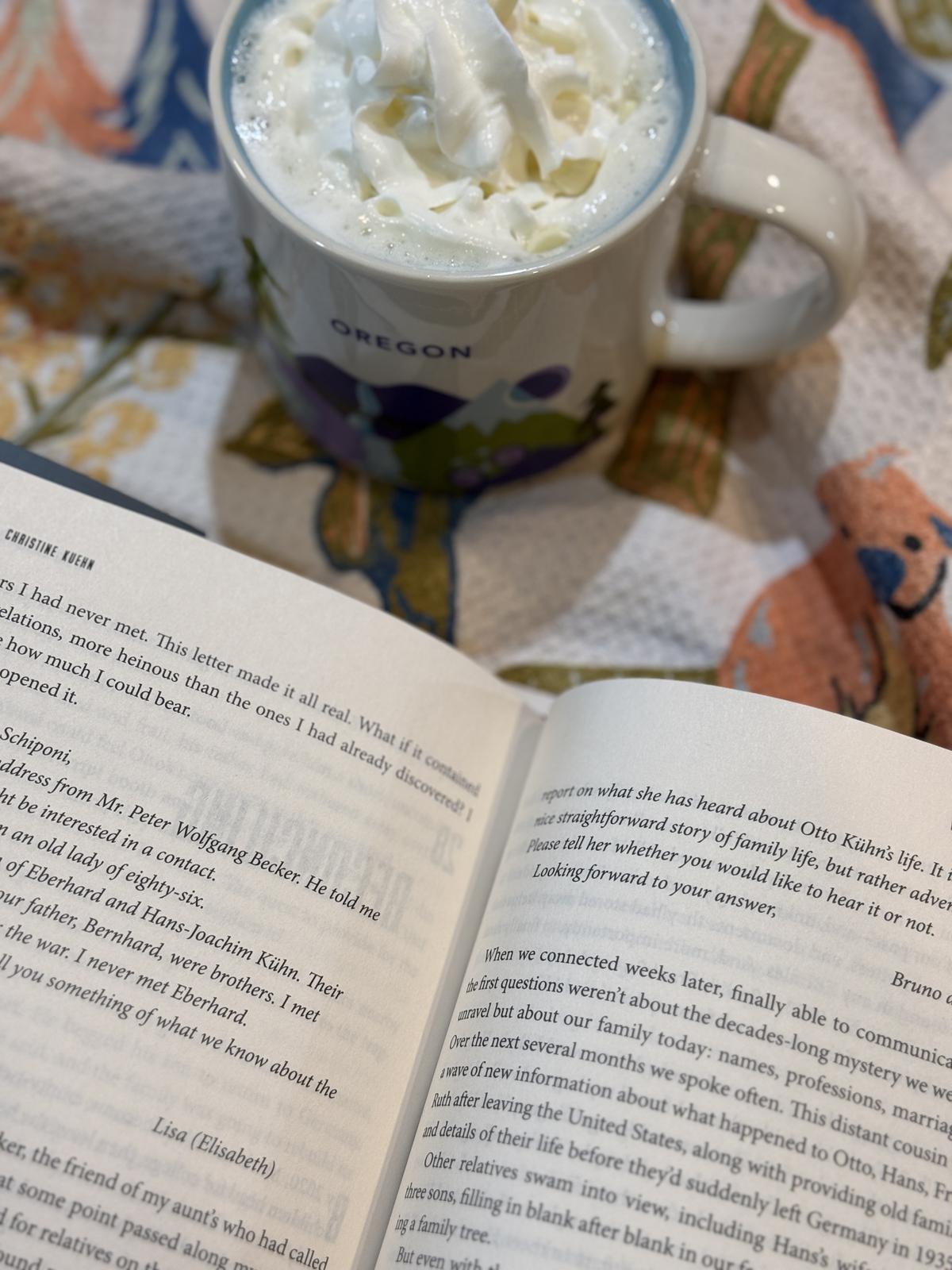 book and cup of white hot chocolate with whipping cream
