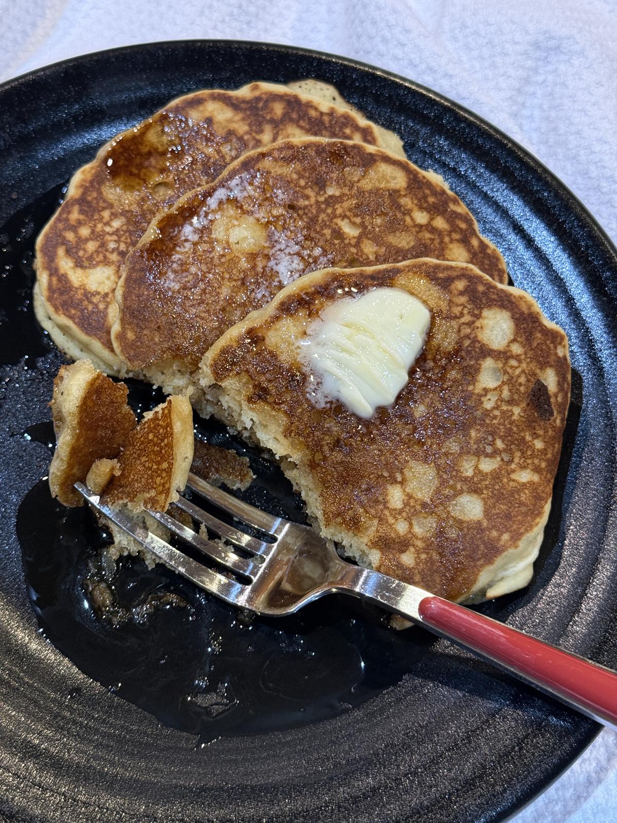 gluten free sourdough pancakes with fork on black plate