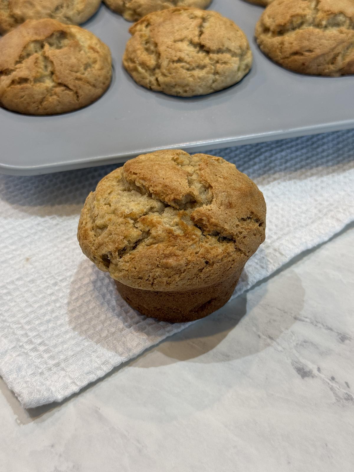 peanut butter muffin on white background with pan of muffins in background