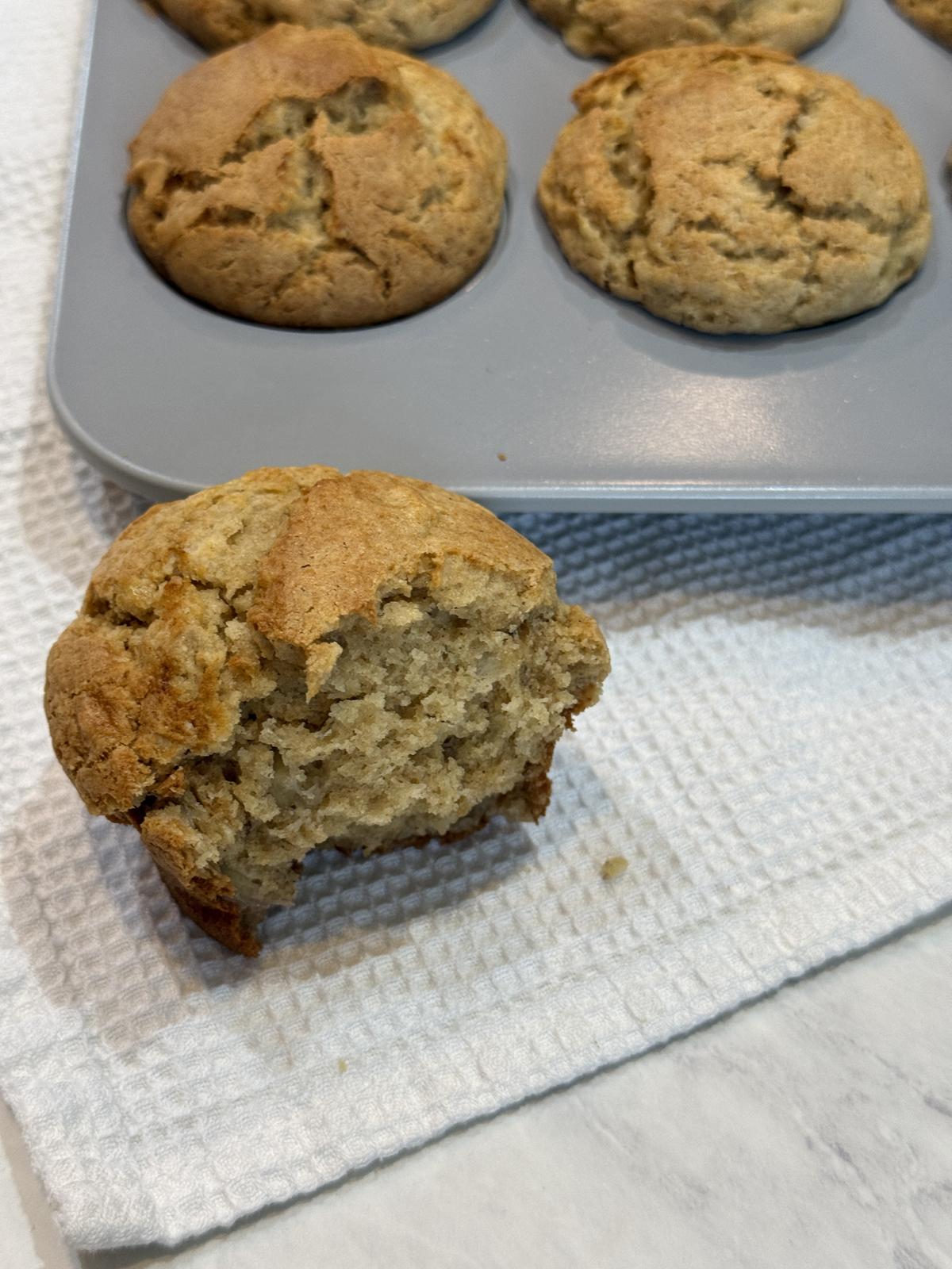 peanut butter banana muffin on white napkin with pan of muffins in background