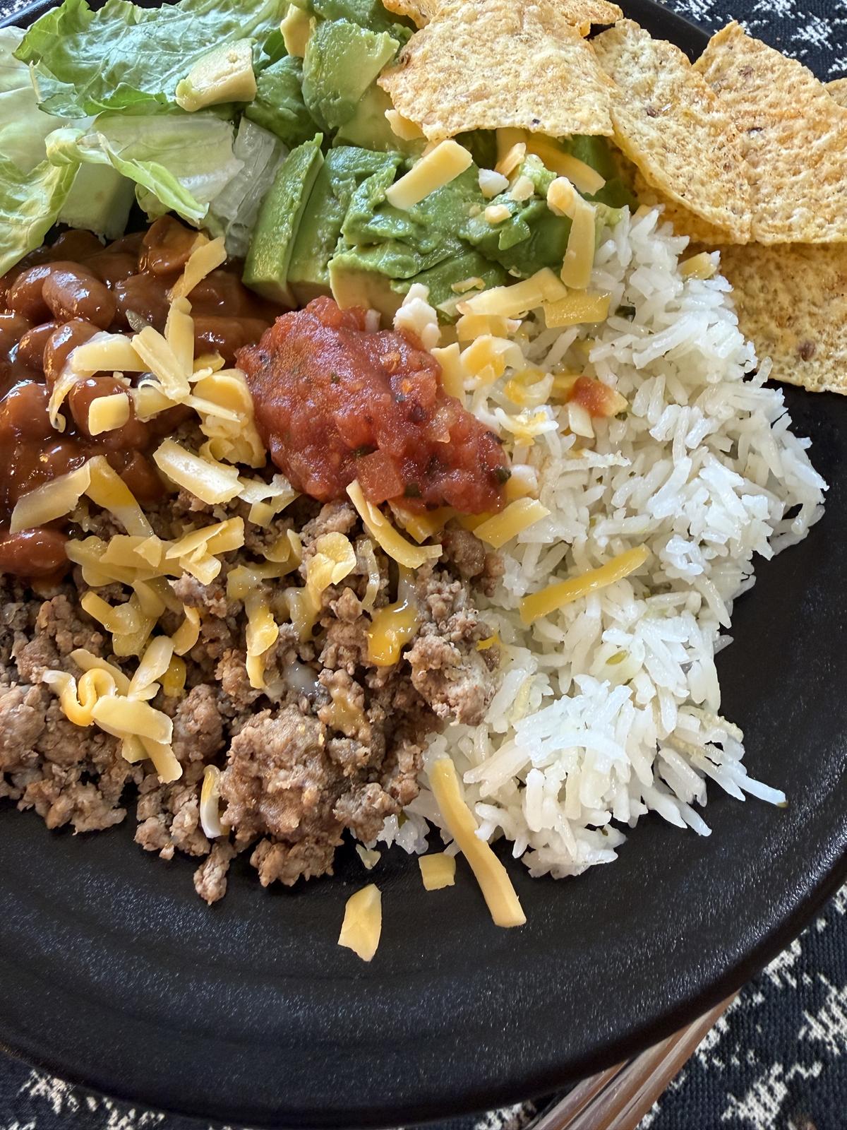 Cilantro Lime Rice with meat cheese beans and chips on black plate