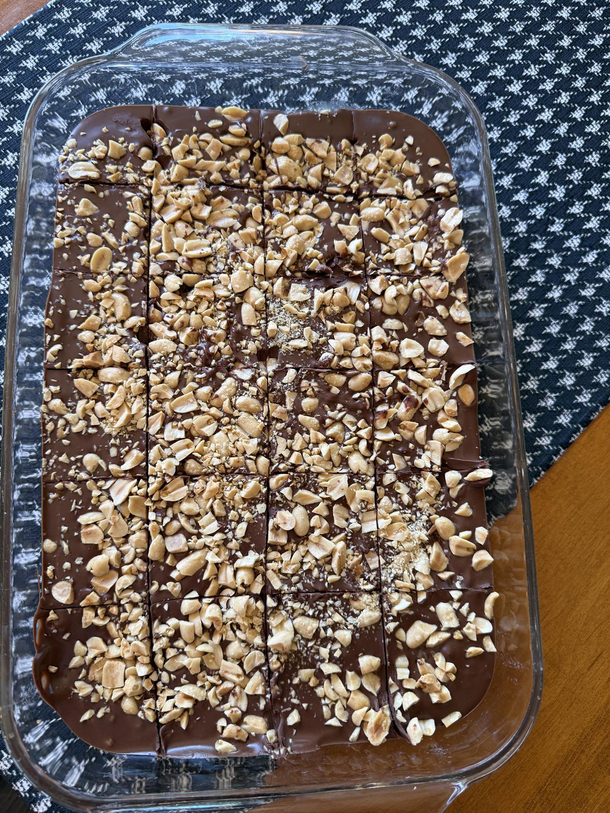 No Bake Peanut Butter Bars with peanuts on top in glass pan on black and white table runner