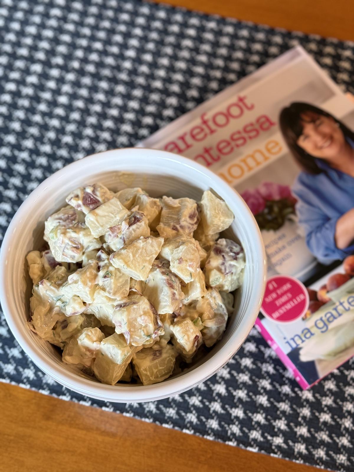 potato salad in white bowl with Ina Garten cookbook in background
